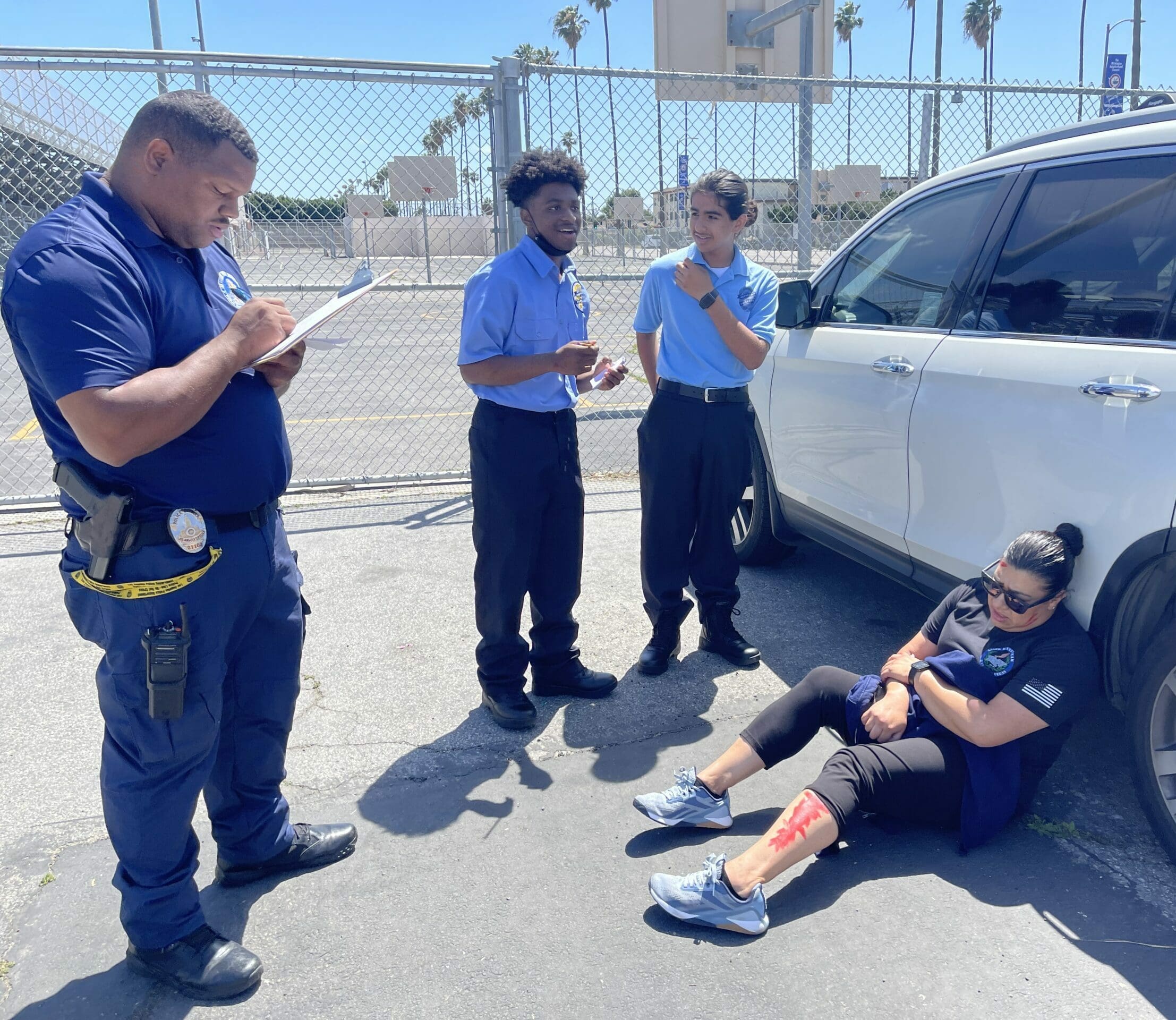 A Police Officer and a Student Stand Near an Injured Woman