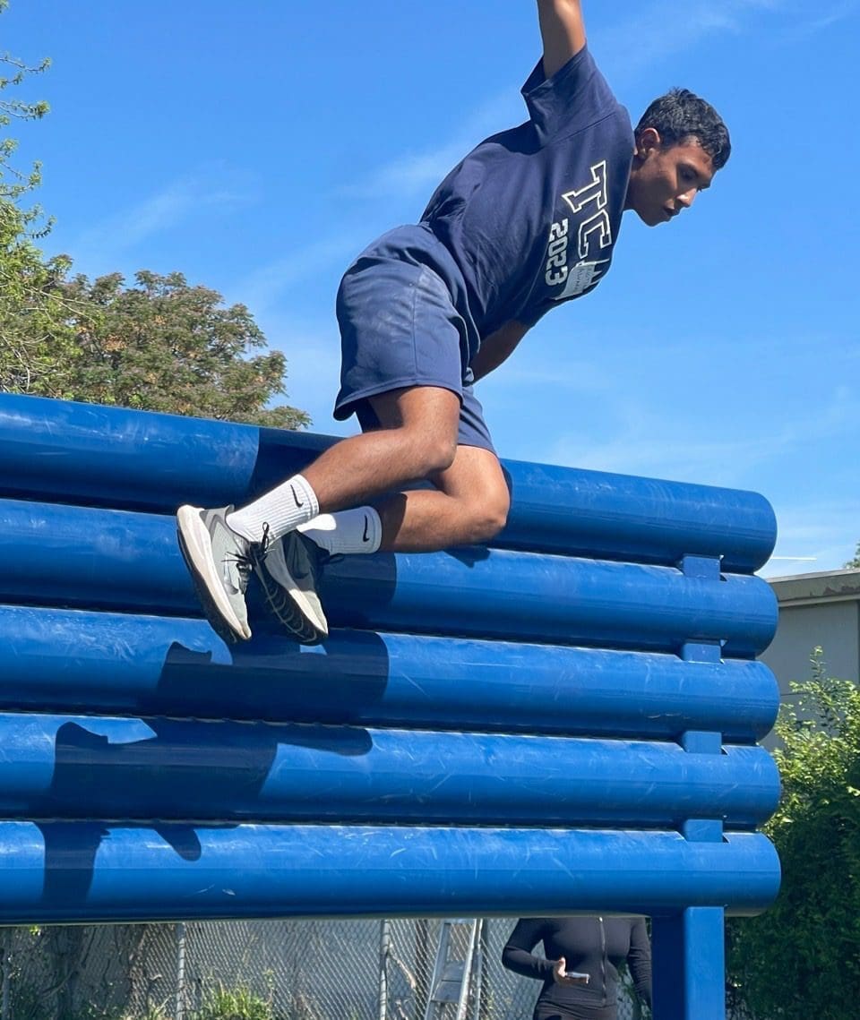 A Person Jumping Over a Blue Structure